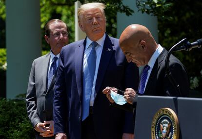Donald Trump looks on as former GlaxoSmithKline pharmaceutical executive Moncef Slaoui removes his face mask during a coronavirus response event in the Rose Garden at the White House in May of this year.