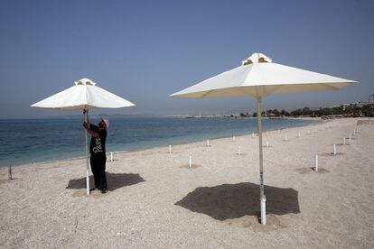 Un trabajador coloca sombrillas en una playa en la zona costera de Atenas (Grecia).