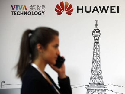 Uma mulher passa em frente a um logotipo da Huawei, neste domingo em Paris.