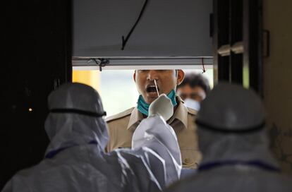 Un sanitario toma una muestra a un hombre para detectar coronavirus, en Prayagral (India).
