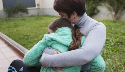 Madre e hija se abrazan sin querer pensar en una posible separación.