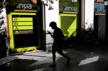 MADRID, 04/09/2020.- Una persona camina por el centro de Madrid delante de una sucursal de Bankia.