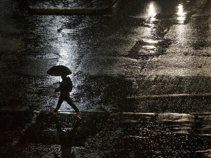 Un hombre camina bajo la lluvia en una calle de Santiago.