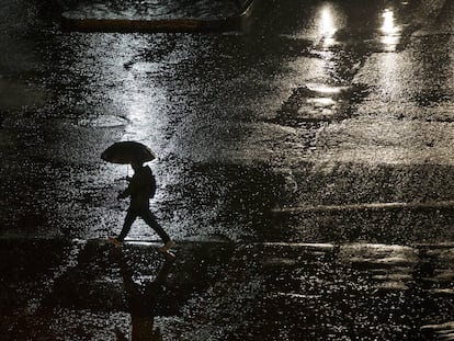 Un hombre camina bajo la lluvia en una calle de Santiago.
