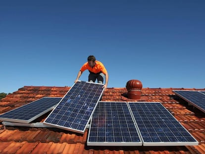 Un operario coloca paneles solares sobre un tejado.