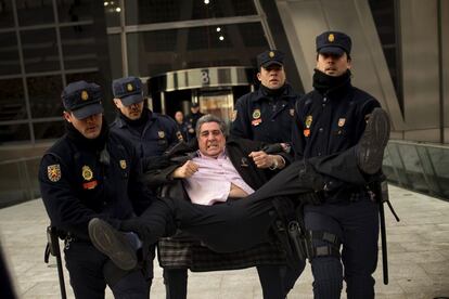 Un miembro de la Plataforma de Afectados por la Hipoteca es sacado por la policía tras haber entrado en la sede central de Bankia.