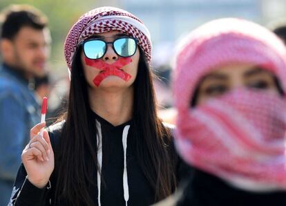Una estudiante universitaria con una cruz de cinta adhesiva en la boca (símbolo que reivindica la libertad de expresión) participa este jueves en una protesta en Bagdad (Irak).