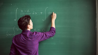 Un chico resuelva un problema matemático en la pizarra.