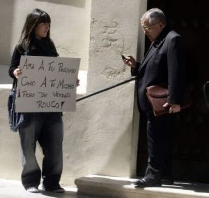 Una indignada del 15-M espera con un cartel a las puertas del Oratorio de San Felipe Neri en Cádiz, a que salga el presidente de la Conferencia Episcopal Española Antonio Rouco Varela.