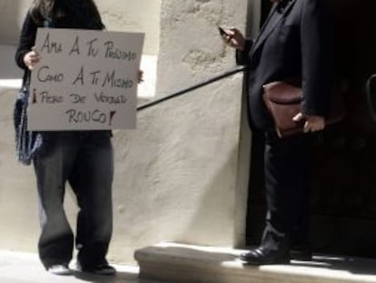 Una indignada del 15-M espera con un cartel a las puertas del Oratorio de San Felipe Neri en C&aacute;diz, a que salga el presidente de la Conferencia Episcopal Espa&ntilde;ola Antonio Rouco Varela.
 