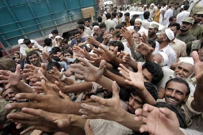 Pakistaníes afectados por las inundaciones tratan de conseguir alimentos durante un reparto de ayuda