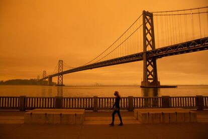 Una mujer camina por el embarcadero, en las cercanías del puente de la Bahía de San Francisco, bajo un cielo lleno de humo, por los incendios en California.