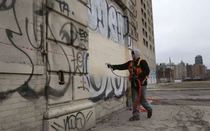 Un empleado p&uacute;blico pinta un edificio en el centro de Detroit