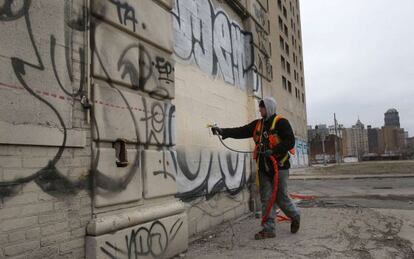 Un empleado público pinta un edificio en el centro de Detroit