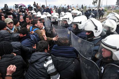 Migrantes ante una barrera policial, este domingo en Idomeni.