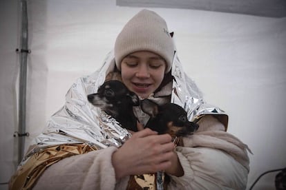 Katya sostiene a sus dos perros después de huir de Ucrania, en el cruce fronterizo de Medyka (Polonia), el 9 de marzo de 2022. Los desplazados de todas partes de Ucrania cargan con lo que pueden arrastrar consigo, incluyendo a sus mascotas.