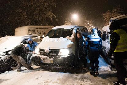 Un grupo de personas intenta mover un coche atrapado en la nieve en una carretera al suroeste de París. El ministerio del Interior ha aconsejado a los franceses que dejen los coches en casa debido a esta situación que ha calificado como “excepcional”.