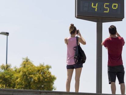 Unos jóvenes hacen una fotografía a un termómetro que marca 45 centígrados en Sevilla el pasado día 18.
 