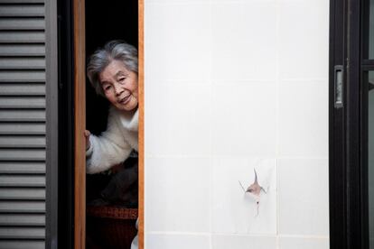 La fotógrafa, Kimiko Nishimoto, posa junto a un retrato suyo en la ventana de su casa. "Para ser sincera, no pienso mucho en lo que la fotografía significa para mí, solo entento traer alegría a la gente. Hacer fotos es el secreto de mi felicidad y seguiré haciéndolo mientras siga viva".