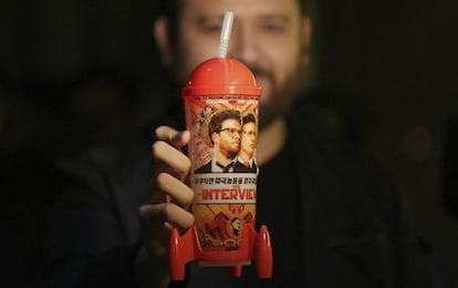 Un hombre muestra una taza de recuerdo del estreno de &#039;The Interview&#039;. 