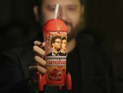 Un hombre muestra una taza de recuerdo del estreno de 'The Interview'.