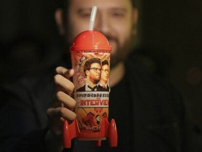 Un hombre muestra una taza de recuerdo del estreno de &#039;The Interview&#039;. 