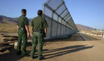 Dos polic&iacute;as vigilan la frontera de M&eacute;xico y EE UU.