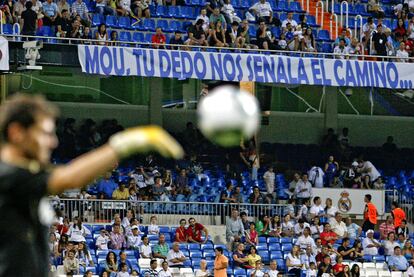 Casillas, suplente anoche, calienta antes del partido ante una pancarta de apoyo a Mourinho colgada en el primer anfiteatro.