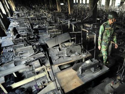 Un polic&iacute;a inspecciona unos talleres de confecci&oacute;n de ropa tras incendiarse en Dacca (Bangladesh), el pasado noviembre.