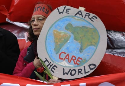 El presidente francés, François Hollande, pidió hoy a los delegados de las 196 partes que participan en la cumbre sobre el clima (COP21) que adopten el texto presentado, porque "será un gran acto para la humanidad". En la imagen. una activista muestra un mapa durante la manifestación en París.