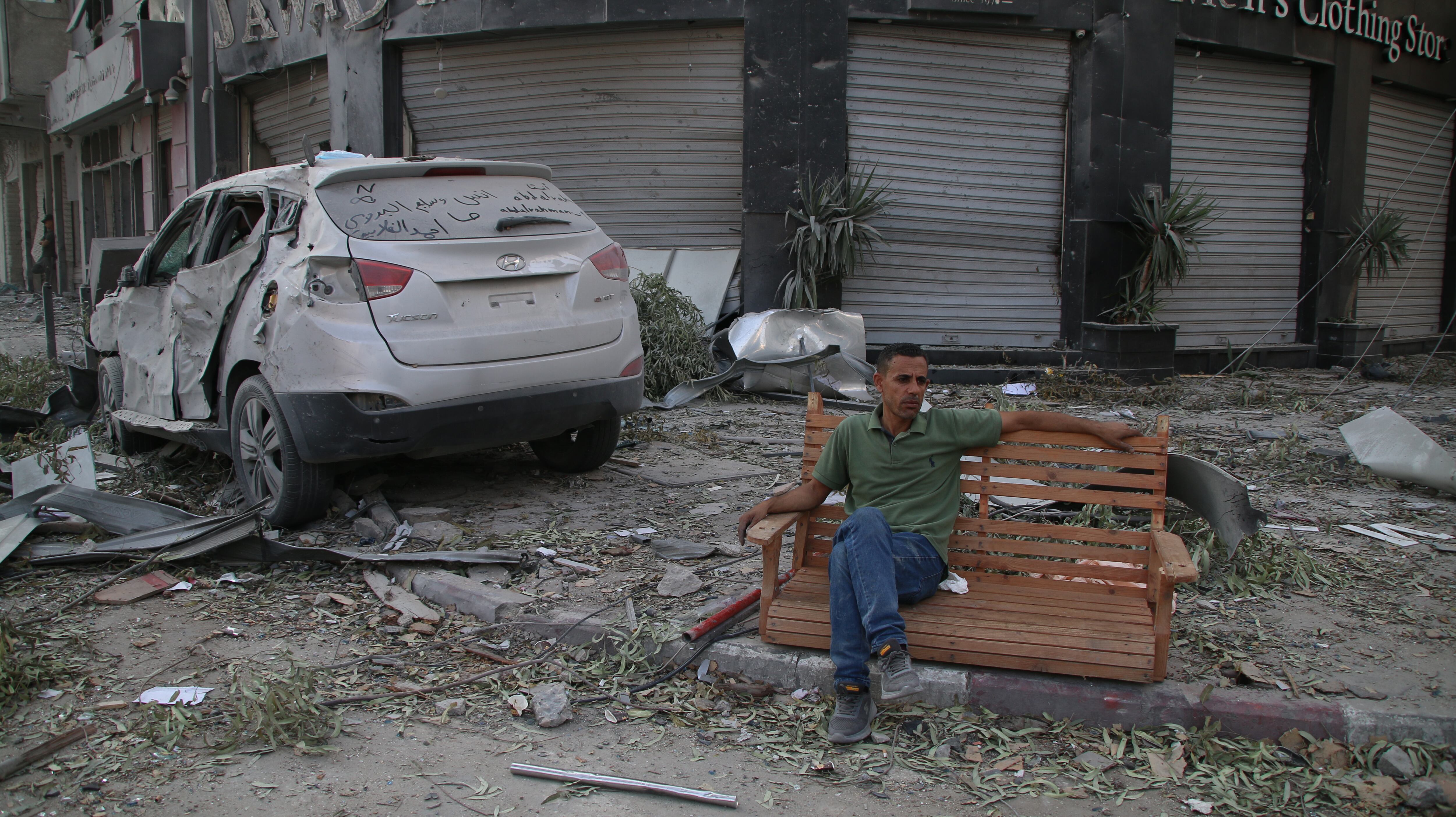 Un ciudadano palestino, sentado, observa los daños causados por ataques aéreos isaraelíes