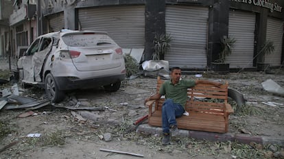 Un ciudadano palestino, sentado, observa los daños causados por ataques aéreos isaraelíes