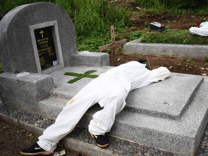 Dos sepultureros exhaustos descansan entre las tumbas de un cementerio destinado a víctimas del Covid-19 en Bandung, Indonesia.