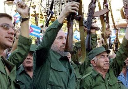 El presidente de Cuba, Fidel Castro (centro), levanta un fusil AK-47 durante la ceremonia de celebración de los 40 años de socialismo en la isla.