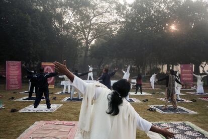 Varias personas se estiran durante una sesión de yoga en los jardines Lodhi de Nueva Delhi (India).