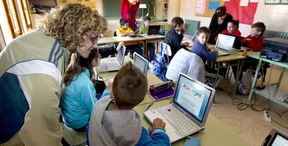 Varios niños dan clase con ordenadores.