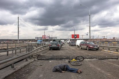 Un cadáver, en una carretera, junto a coches abandonados por la población en un puente destruido por los ataques del ejército ruso en Irpin, el 7 de marzo.