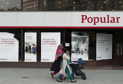 Unas mujeres pasan ante una oficina del Banco Popular en Barcelona. EFE/Archivo