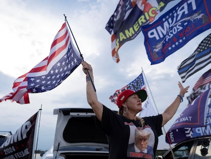 Una seguidora de Trump lleva la bandera estadounidense de cabeza, este jueves cerca de la residencia del expresidente en Palm Beach (Florida).