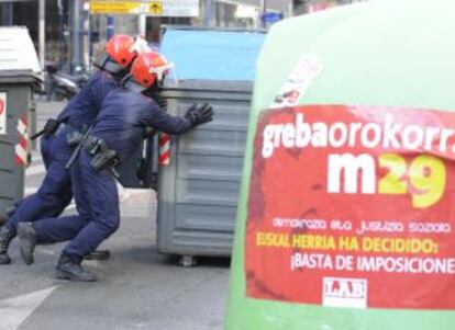 Agentes de la Ertzaintza retiran uno de los contenedores cruzados en una calle de Vitoria.