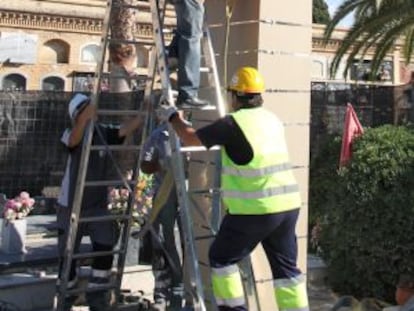 Varios operarios retiran el monolito de la fosa común del cementerio de Paterna esta mañana.