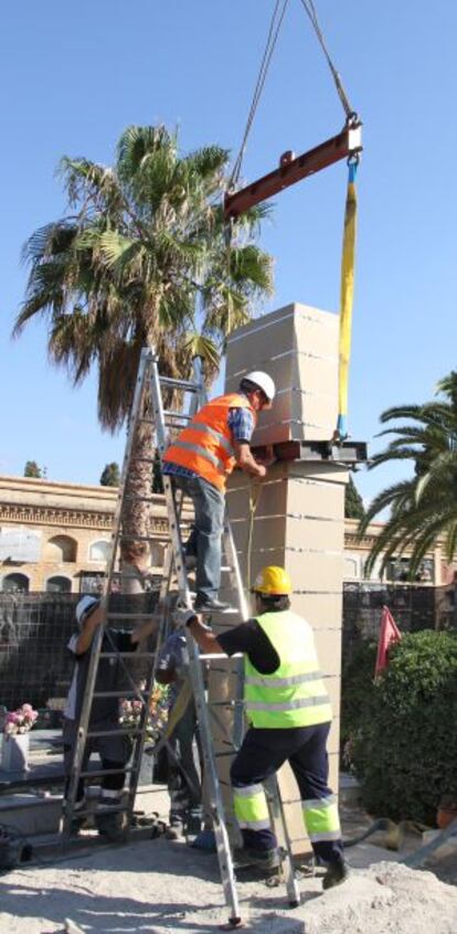 Varios operarios retiran el monolito de la fosa común del cementerio de Paterna esta mañana.