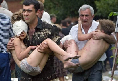 Dos hombres llevan en brazos a sendos ni&ntilde;os liberados tras el asalto de las fuerzas rusas en Beslan, en 2004 (archivo). 
 