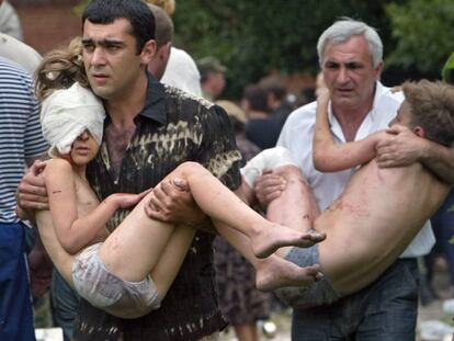 Dos hombres llevan en brazos a sendos ni&ntilde;os liberados tras el asalto de las fuerzas rusas en Beslan, en 2004 (archivo). 
 