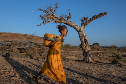 Una mujer de Tigray que huyó del conflicto en esta región de Etiopía, lleva agua a la espalda en un campamento de refugiados en Sudán.