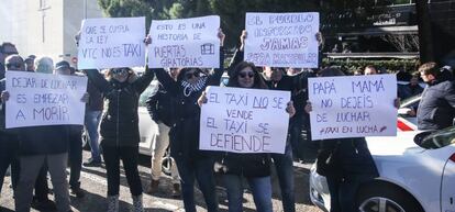 Varias personas portan carteles reivindicativos en la asamblea de taxistas.