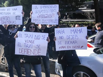 Varias personas portan carteles reivindicativos en la asamblea de taxistas.