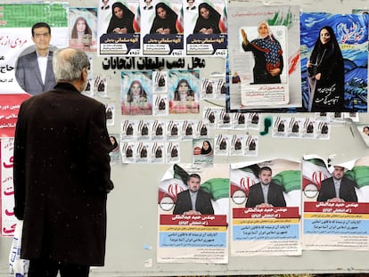 Un hombre mira los carteles electorales de los candidatos que se presentarán en las elecciones parlamentarias iraníes, este lunes en Teherán.