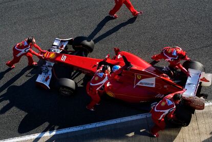 Los mecánicos del equipo Ferrari asisten a Fernando Alonso en su llegada a boxes.