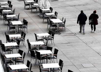 Dos personas caminan por el centro de Pamplona con las terrazas de los bares vacías.